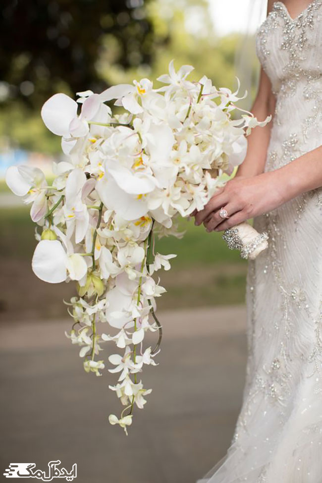 دسته گل عروس با مدل آبشاری و تزئین مروارید در قسمت ساقه گل‌ها