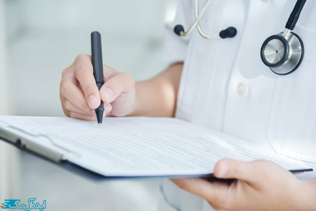 نمای نزدیک از پزشکی که روی یک برگه در حال نوشتن است