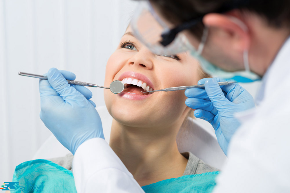 دندانپزشک دندان‌های یک زن جوان را معاینه می‌کند