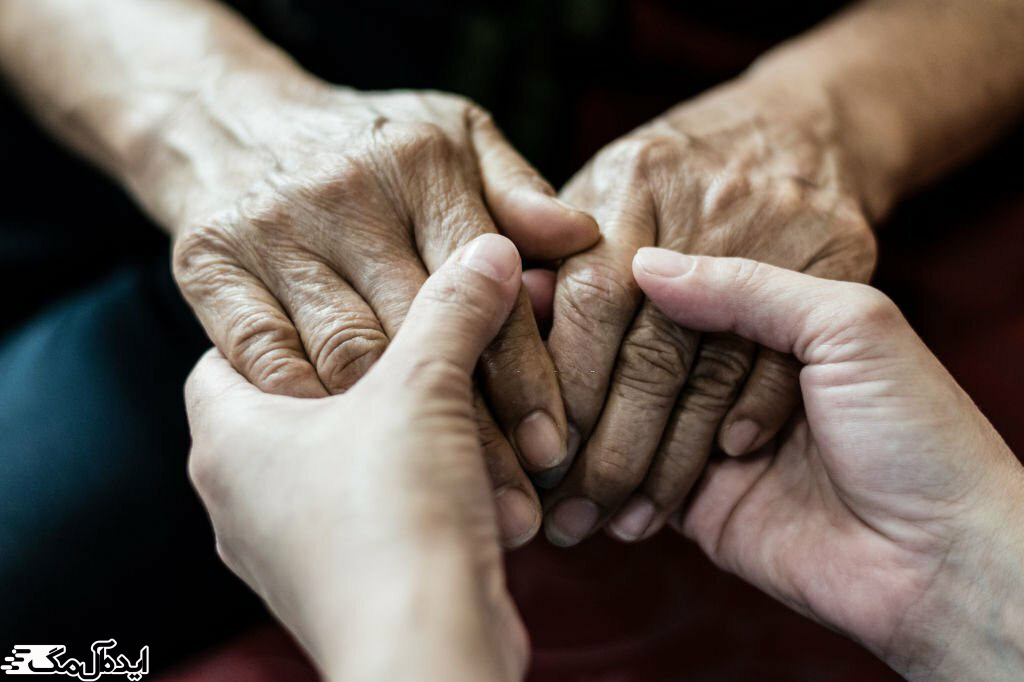یک فرد جوان دست‌های یک سالمند را گرفته است