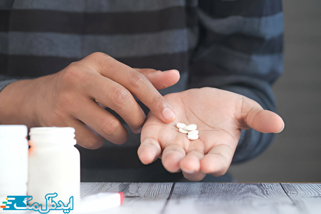 فردی که چند عدد قرص باکلوفن در کف دست خود ریخته است