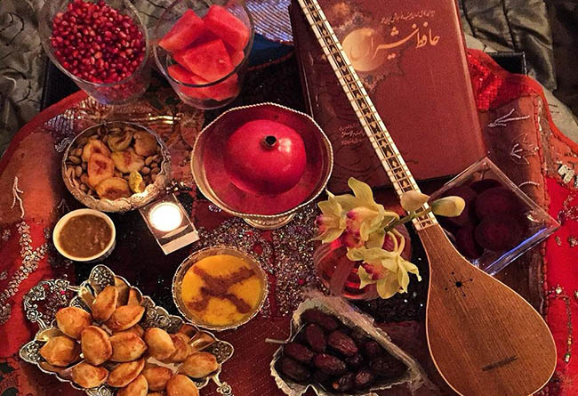 میز و سفره شب یلدا شامل دیوان حافظ، انار، هندوانه و سه تار