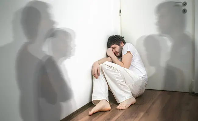 یک مرد مبتلا به اسکیزوفرنی در گوشه اتاق نشسته است