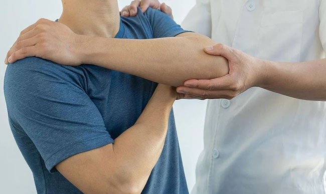 یک فیزیوتراپ مرد مشغول درمان و فیزیوتراپی شانه یک مرد بیمار است