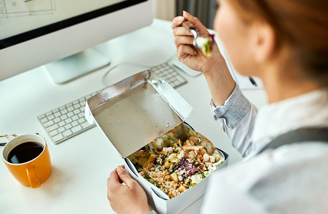 یک زن در حال خوردن غذا در سر کار است