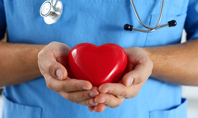 یک پزشک یک قلب قرمز را در دست گرفته است